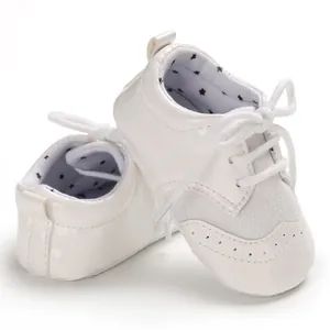 Detailed view of white patent leather baby walking shoes with elegant brogue design