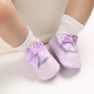 Gros plan de chaussures bébé princesse lavande avec broderies florales et nœuds ruban