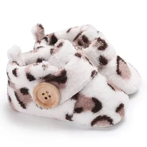 Close-up of plush baby booties with leopard print and wooden button detail