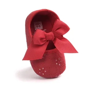Close-up of red baby princess shoe featuring a large bow and delicate embroidery detail