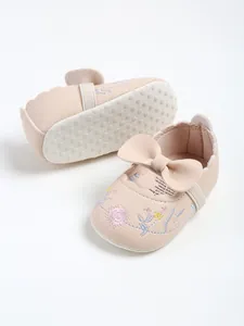 Detail view of pink embroidered baby princess shoes with a bow and soft non-slip sole