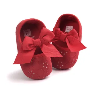 Detailed view of red embroidered baby shoes with a large decorative bow.