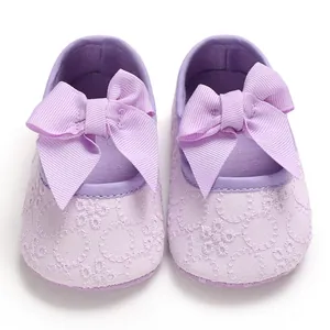 Gros plan de chaussures bébé violettes avec texture en dentelle et grands nœuds en ruban