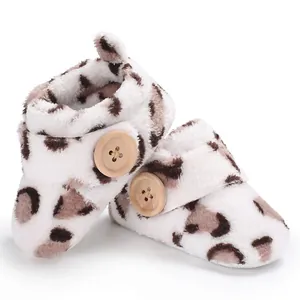 Close-up of leopard print plush baby booties featuring a large decorative wooden button