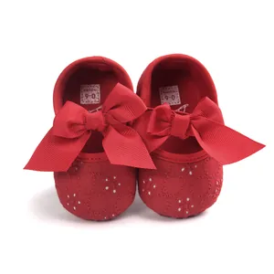 Detailed view of red embroidered baby shoes with soft soles and decorative ribbon bows