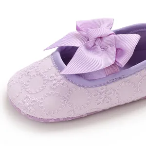 Gros plan de chaussure princesse bébé violette avec broderie et nœud papillon.