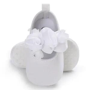 Vorderansicht weißer Baby-Prinzessinenschuhe mit Stoffblume und gepunkteten Sohlen.
