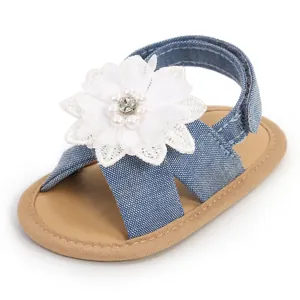 Détail d'une sandale en denim pour bébé fille avec fleur en dentelle et perles