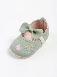 Close-up detail of sage green baby princess shoes with floral embroidery and leather bow