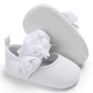 Weiße Baby Mädchen Prinzessin Lauflernschuhe mit Stoffblumen und rutschfester Sohle im Detail.