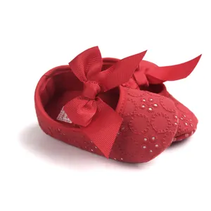 Detailed view of red baby princess shoes with floral embroidery and a large ribbon bow.