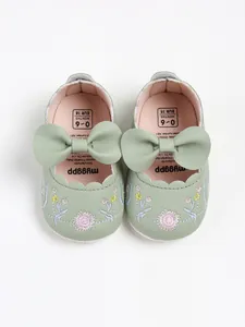 Detailed view of green baby princess shoes with floral embroidery and soft leather bows