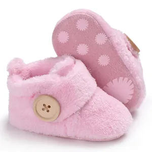 Close-up of soft pink plush baby walking boots with wooden button and anti-slip sole