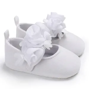 Nahaufnahme weißer Prinzessinnenschuhe für Babys mit zarter Stoffblumendekoration