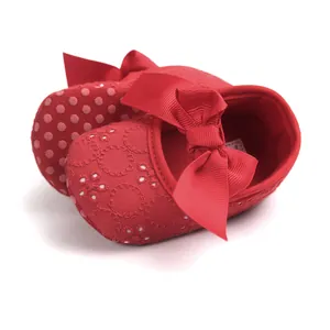 Close-up of red embroidered baby princess shoes featuring a large decorative ribbon bow