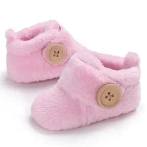 Detailed view of pink fluffy baby booties with decorative wooden buttons on side