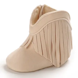 Detailed view of beige faux suede baby boots with stylish fringe tassels for newborn girls.