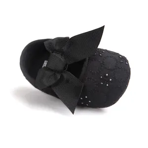 Top view detail of black baby princess shoe with large ribbon bow and embroidery
