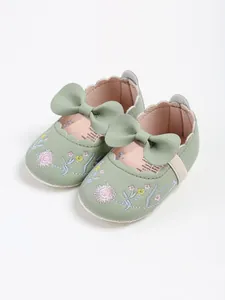 Detail of sage green vintage baby princess shoes with floral embroidery and bow