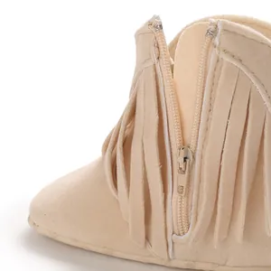 Close-up detail of beige infant fringe boots showing side zipper and soft suede texture