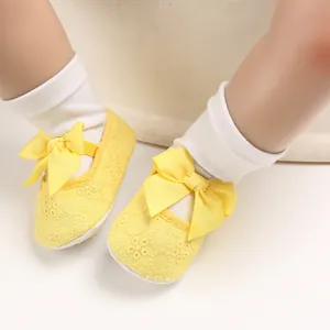 Gros plan de chaussures de marche jaunes pour bébé avec semelles souples et nœuds