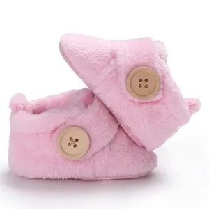 Soft pink fuzzy baby booties with a decorative wood button detail for warm winter comfort