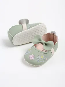 Detailed view of light green baby Mary Jane shoes with floral embroidery and cute bow