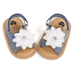 Gros plan sur des sandales bébé en denim bleu avec fleur blanche et semelle souple