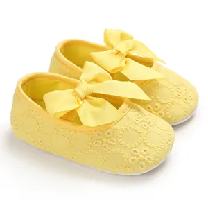 Gros plan de chaussures de bébé en dentelle jaune avec semelles souples et nœuds décoratifs