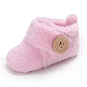 Soft pink plush baby booties featuring a decorative wooden button detail for infants