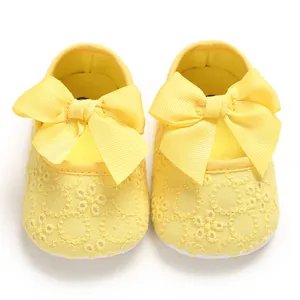 Vue de dessus de chaussures bébé jaunes avec de grands nœuds en satin et dentelle.