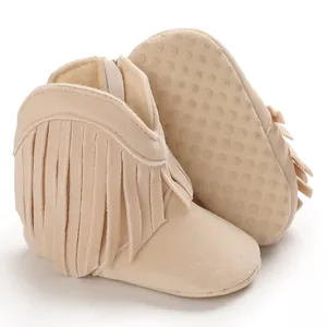 Detailed view of beige fringe baby boots with non-slip dotted sole for pre-walkers.
