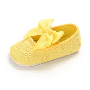 Détail de chaussures princesse bébé jaunes avec nœud ruban et dentelle brodée