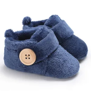 Close-up of navy blue plush baby boots with a large decorative wooden button detail
