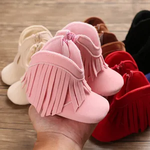 Macro detail of soft suede infant fringe boots featuring side zipper and warm pink color