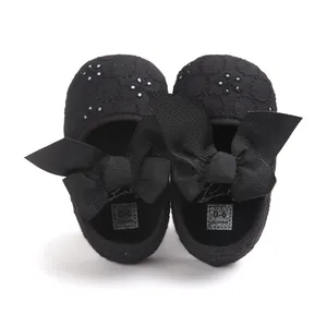 Macro view of black embroidered baby princess shoes featuring large grosgrain bows