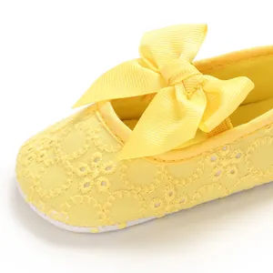 Détail d'une chaussure de princesse jaune pour bébé avec broderie et nœud en ruban