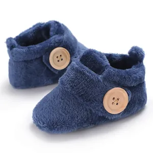 Macro view of navy blue fuzzy infant booties featuring large decorative wooden buttons