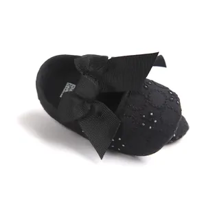 Detailed view of black baby princess shoe featuring a large bow and floral embroidery