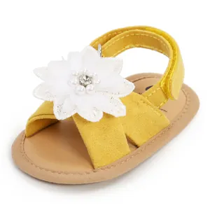 Gros plan d'une sandale jaune pour bébé avec une grande fleur blanche et perles