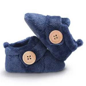 Close-up of navy blue plush baby slippers featuring decorative wooden buttons and soft texture