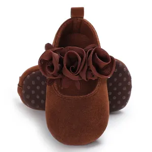 Detailansicht der braunen Samt-Babyschuhe mit Stoffblumenverzierung und weicher Sohle.