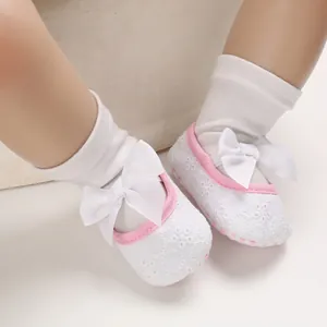 Détail de chaussures de princesse blanches pour bébé avec semelle souple et nœud blanc