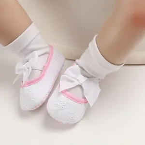 Vue détaillée de chaussures de princesse pour bébé avec broderie et nœuds blancs