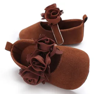 Nahaufnahme von braunen Baby-Prinzessin-Schuhen mit eleganten Stoffblumen und weichen Sohlen