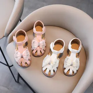 A high-angle view of adorable pink and white toddler girl bow sandals with lace