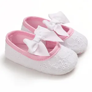 Vue détaillée de chaussures de princesse blanches pour bébé avec nœud rose