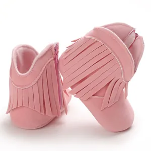Detailed close-up showing pink suede-like baby boots with fringe and side zipper closure