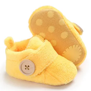 Close-up of soft yellow plush baby shoes showing anti-slip sole and decorative button