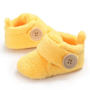 Detailed view of soft yellow plush baby booties with large decorative wood-style button.